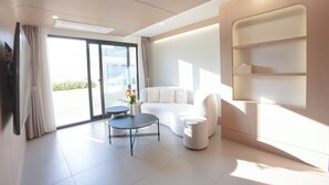 A modern living room with a sofa, a round coffee table, and a TV mounted on the wall. - H-AVENUE Hotel Seomyeon Station (Busan)