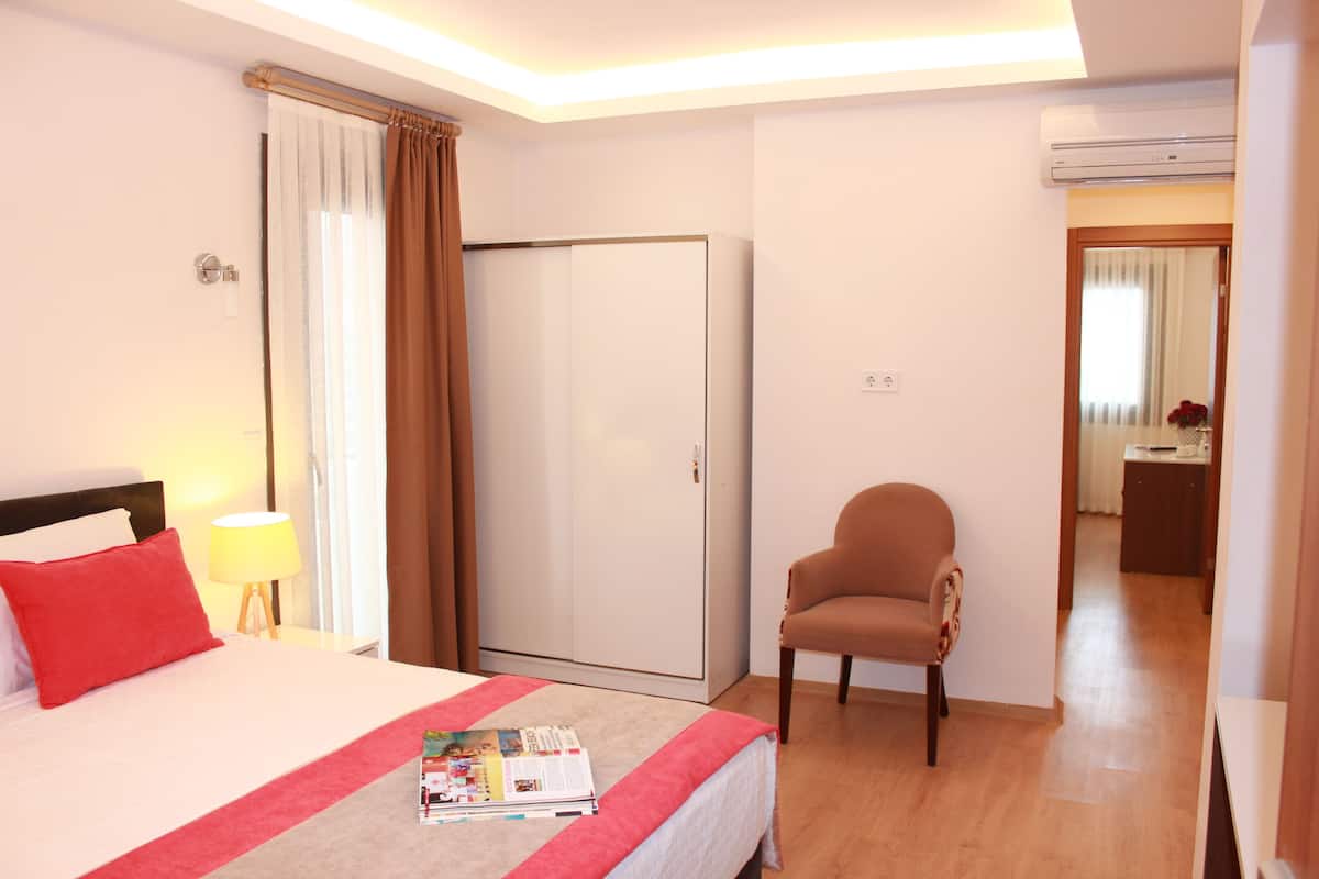 Habitación de hotel con cama, una silla, armario y aire acondicionado.