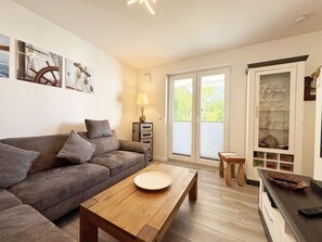 Ein gemütliches Wohnzimmer mit einer Couch, einem Couchtisch und einer Vitrine.