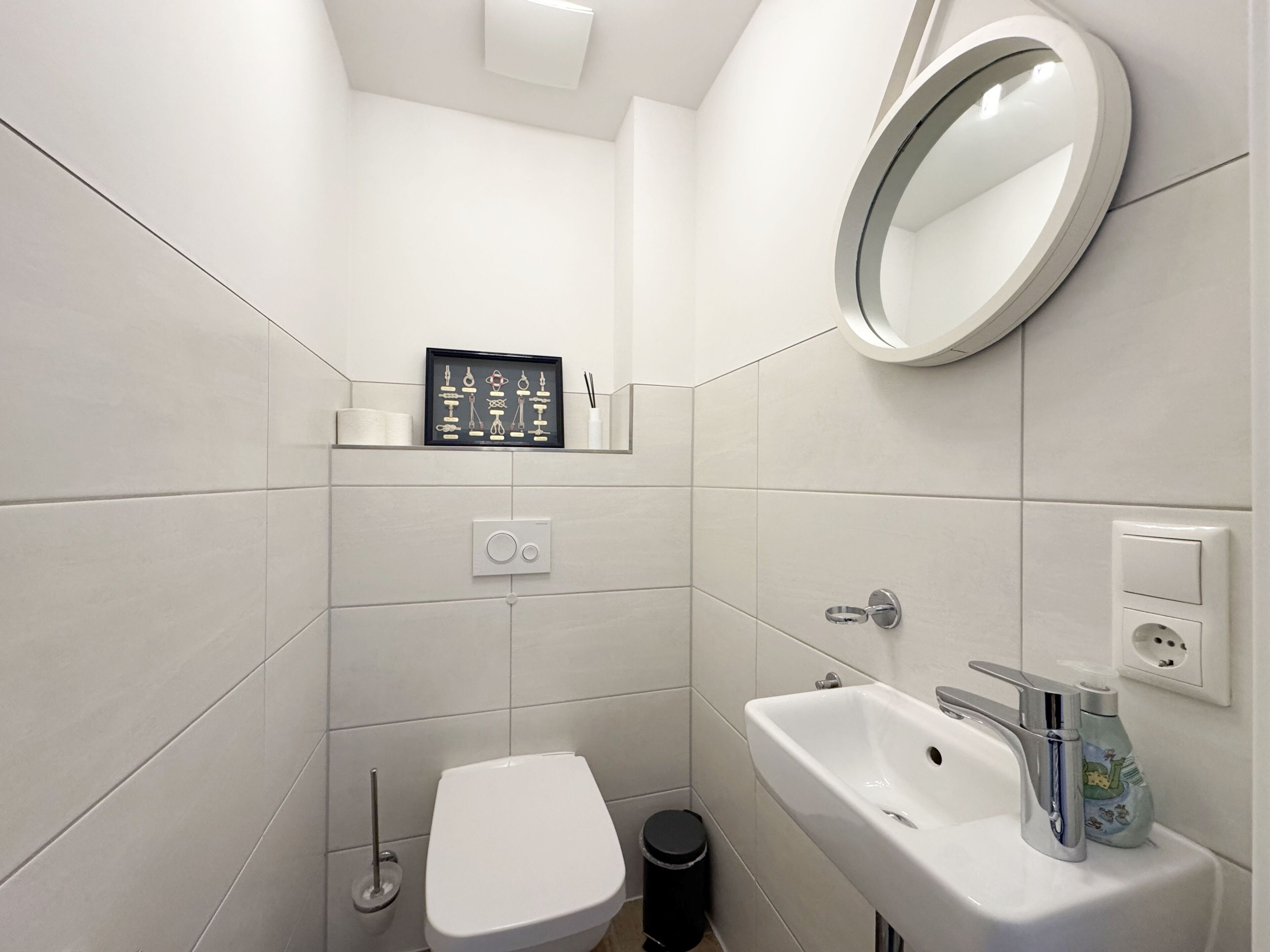A small, modern bathroom with a toilet, sink, and mirror.