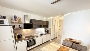Uma cozinha moderna com armários brancos, bancada de madeira e um espaço de refeições com mesa e cadeiras de madeira.