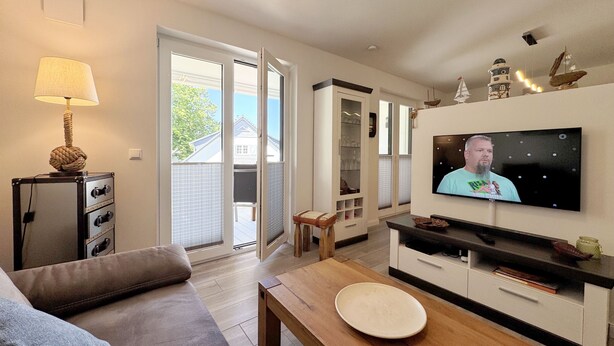 Uma sala de estar com sofá, mesa de centro de madeira, televisão e um armário.