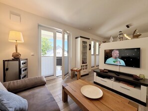 Un salon comprenant un canapé, une table basse en bois, un téléviseur et un meuble.