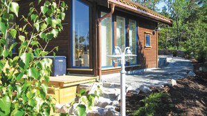 A wooden cabin with large windows, a stone pathway, and a small outdoor seating area. - Stunning home in Risør with sauna (Risør)