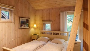 A wooden cabin bedroom with a bed, bedside lamp, and a framed picture on the wall. - Stunning home in Risør with sauna (Risør)