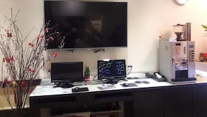 A home office setup with a large flat-screen TV, a desktop computer, and a coffee machine.