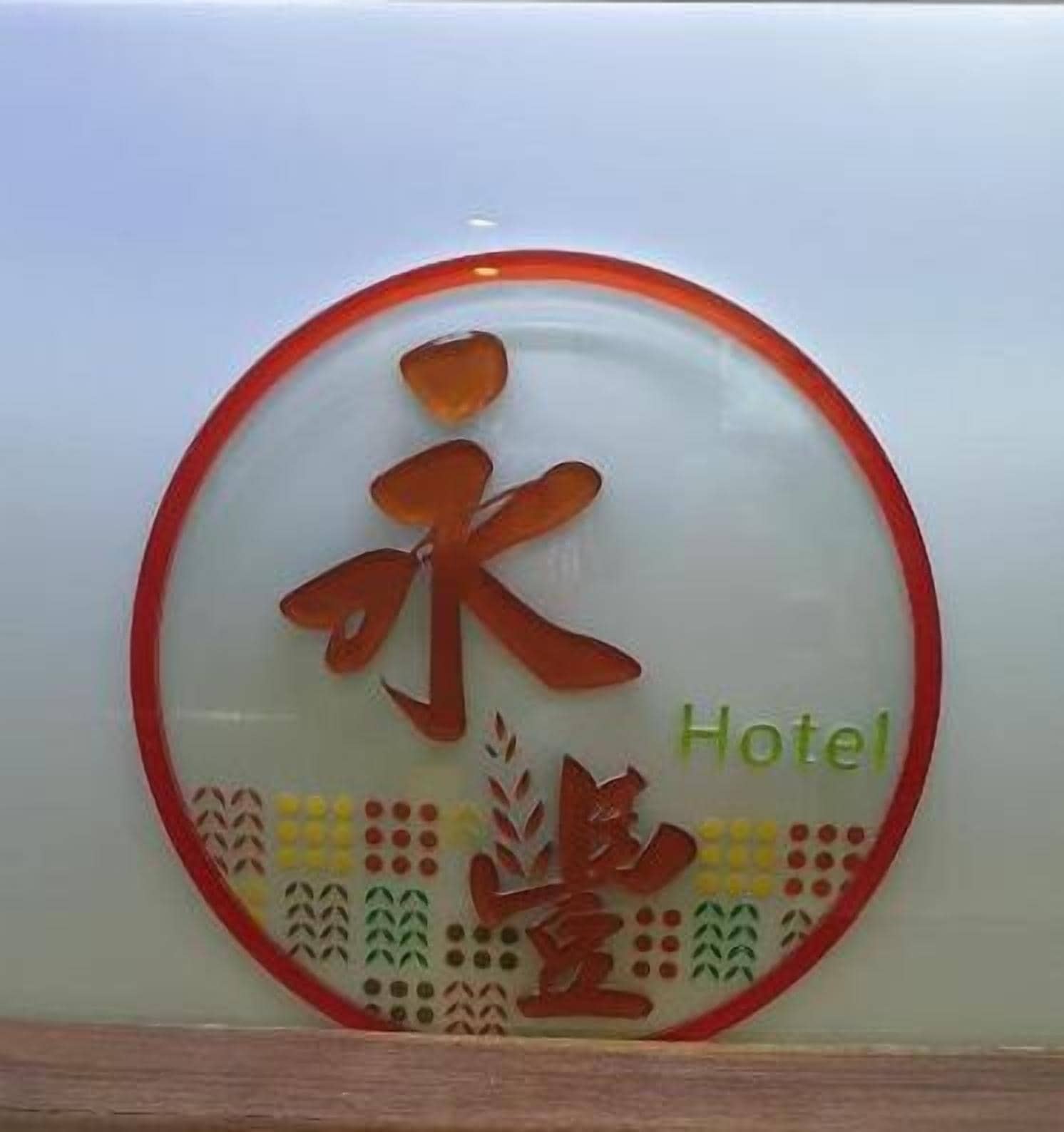 A circular sign with a red border and a central design featuring Chinese characters and the word "Hotel".