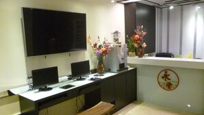 A modern kitchen with a large flat-screen TV, multiple monitors, a coffee machine, and a wooden bench.