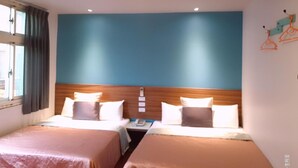 A hotel room with two beds, a wooden headboard, a window with curtains, and a wall with a simple design.