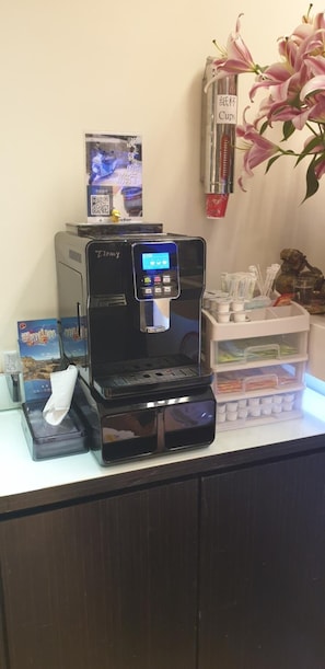 A coffee machine with a digital display, a tissue box, and a small plant on a counter.