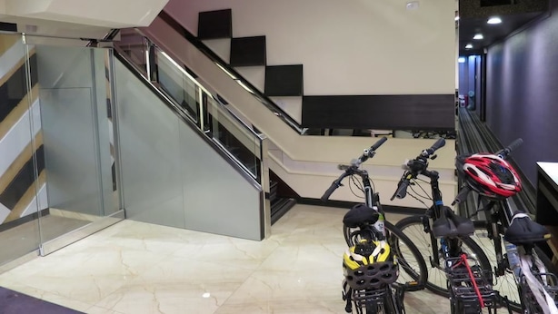 A modern indoor space with a staircase, glass railings, and bicycles.