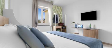 Ein modernes Schlafzimmer mit einem Bett, einem Schreibtisch, einem Fernseher und einem Fenster mit Vorhängen.