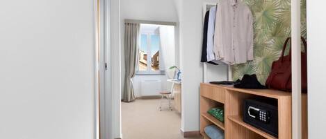 A hotel room with a wooden shelf, a microwave, and a view of the city through a window.
