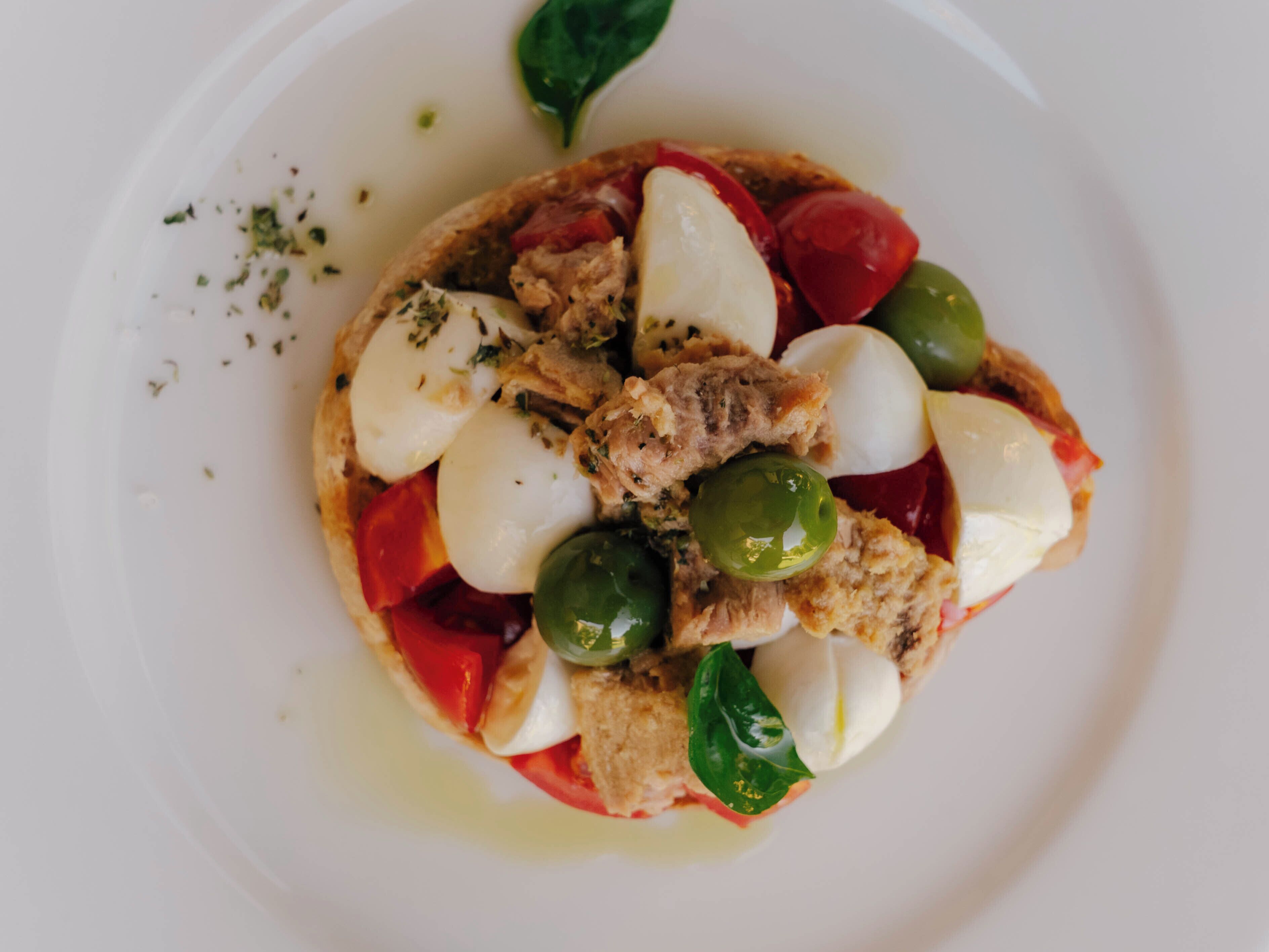A plate of food with tomatoes, mozzarella, olives, and basil.