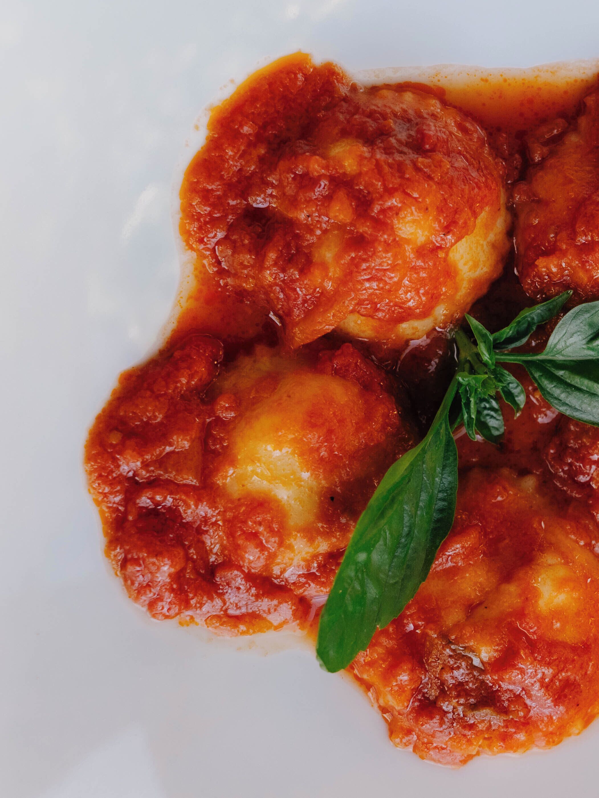 A plate of food with a red sauce and green leaves.
