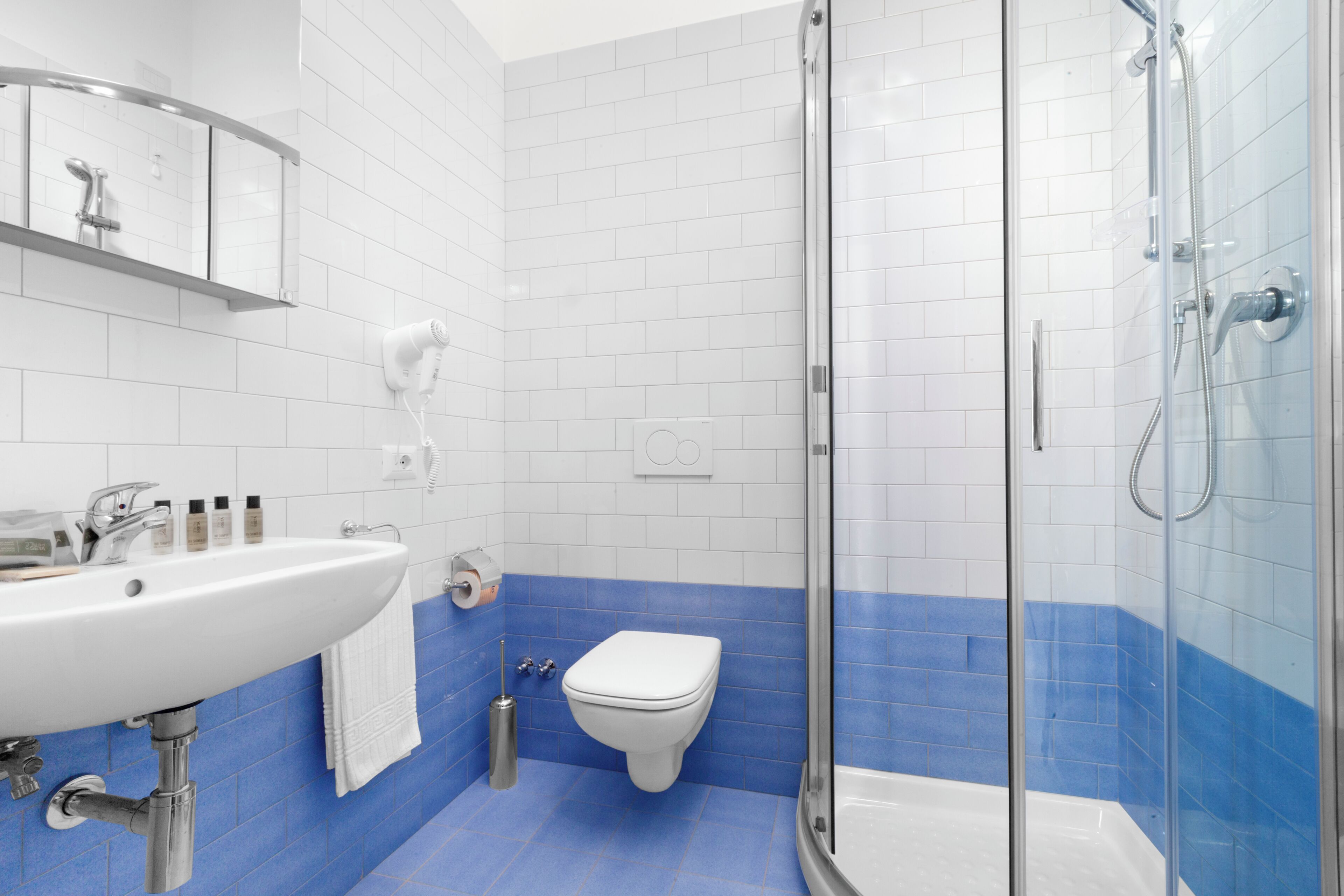 Un baño con lavamanos, inodoro y ducha blancos.