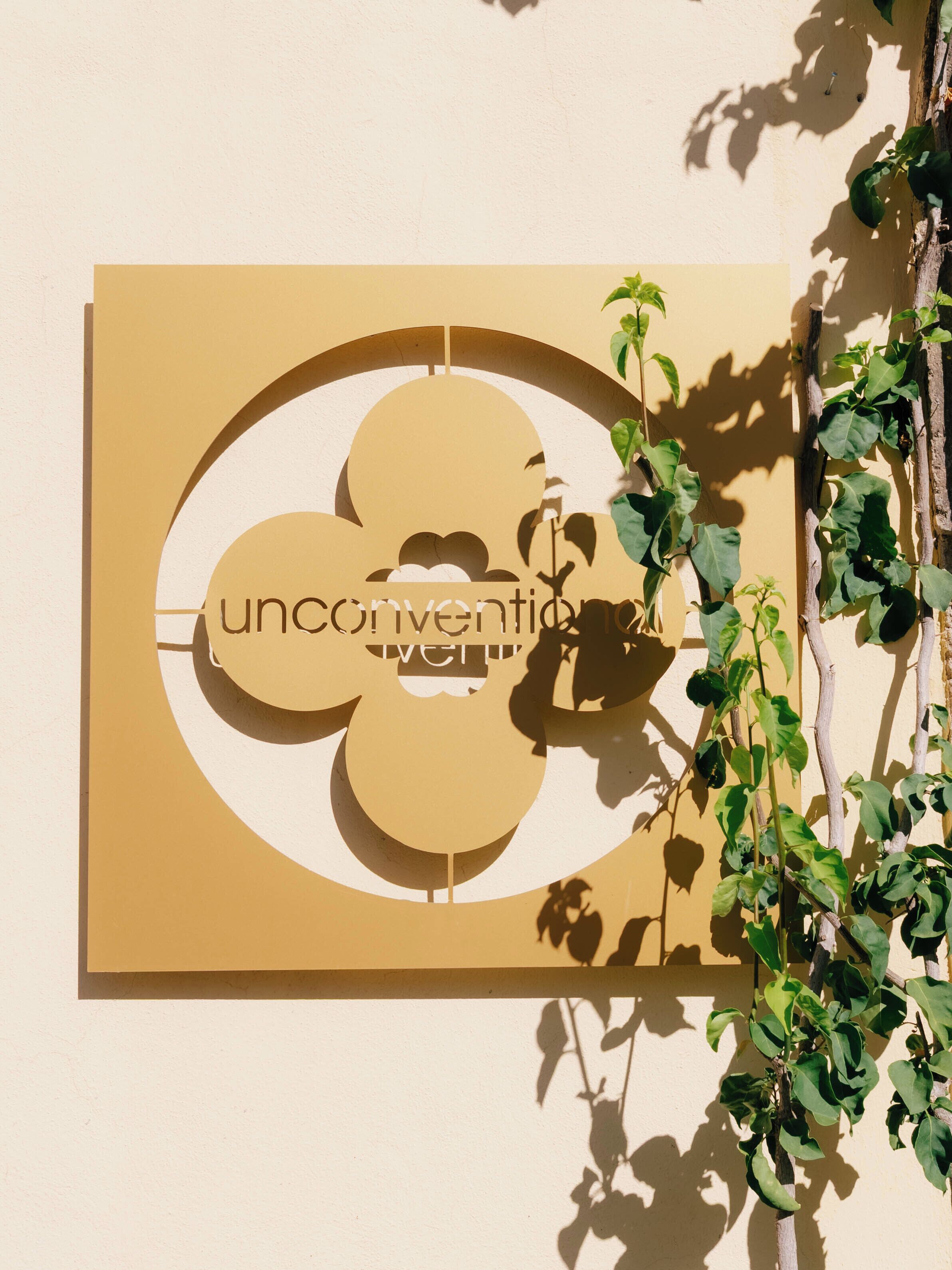 Une enseigne fixée au mur, de forme circulaire, sur laquelle on peut lire le mot « unconvention ».