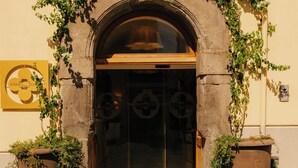 A stone archway entrance with a glass door, flanked by potted plants and a sign. - Unconventional Hotel Sorrento (Sant'Agnello)