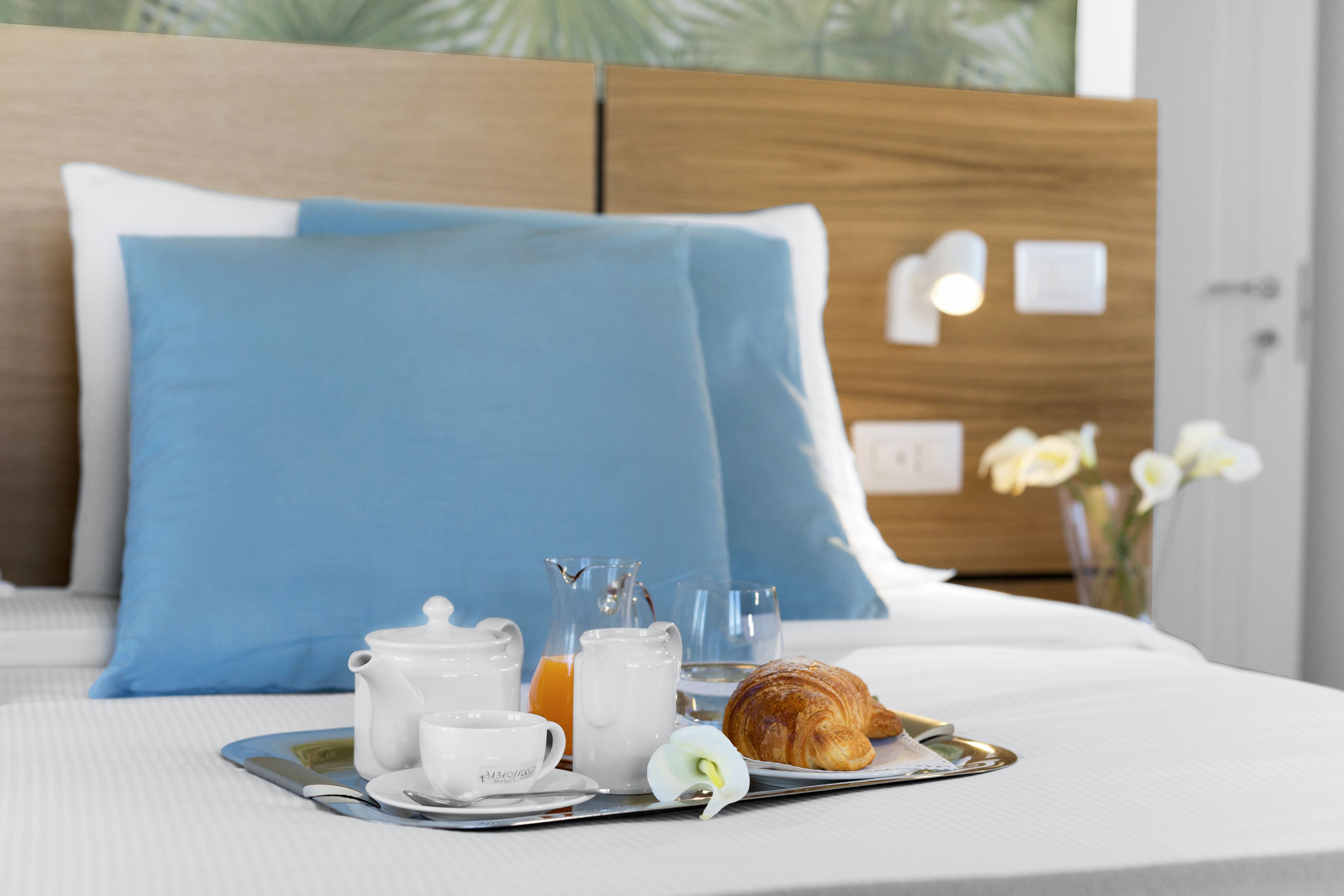 Ein ordentlich bezogenes Bett mit einem blauen und einem weißen Kopfkissen sowie einem Holzkopfteil.