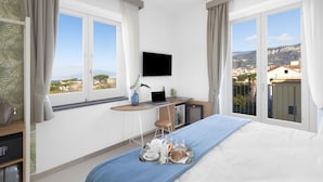 A hotel room with a bed, a desk with a laptop, a TV, and a breakfast tray. - Unconventional Hotel Sorrento (Sant'Agnello)