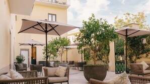 An outdoor seating area with wicker furniture, umbrellas, and potted plants. - Unconventional Hotel Sorrento (Sant'Agnello)