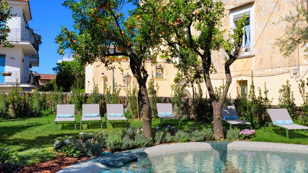 A pool area with lounge chairs and a tree. - Unconventional Hotel Sorrento (Sant'Agnello)