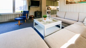 A living room with a sofa, a chair, a coffee table, a fireplace, and a kitchen area. - Cozy home in Farsund with WiFi (Farsund)