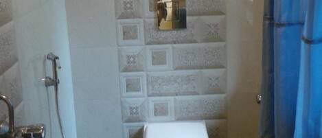A small bathroom with a toilet, a shower, and a blue shower curtain.