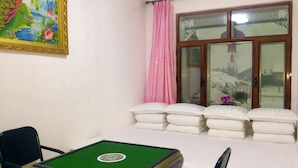 A room with a pool table, a bed with pillows, a window with curtains, and a painting on the wall.