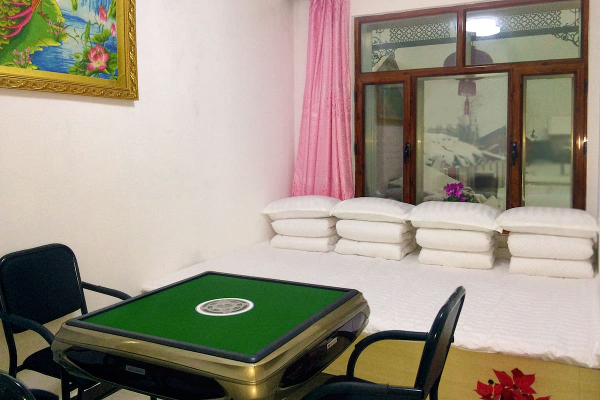 A room with a pool table, a bed with pillows, a window with curtains, and a painting on the wall.
