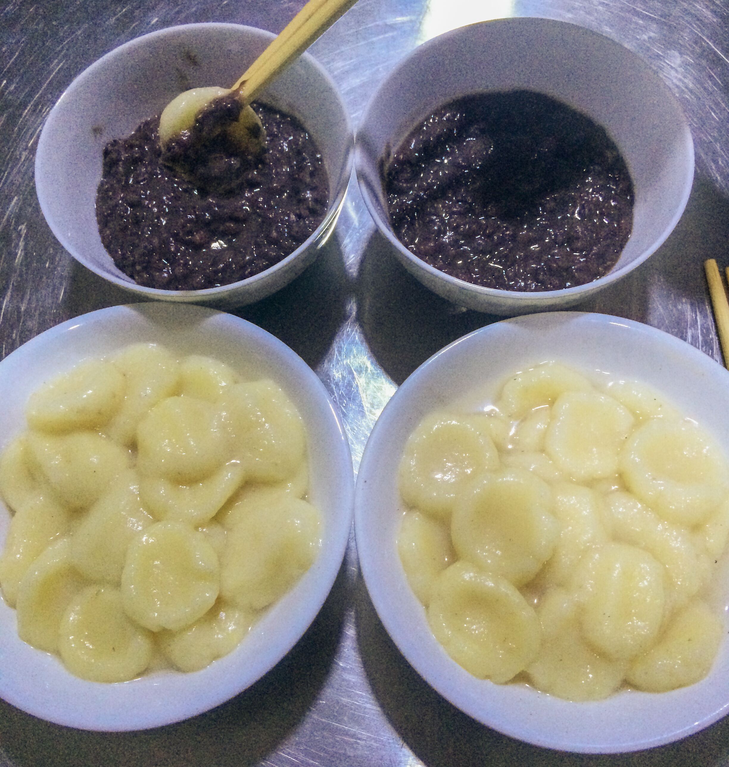 Three bowls of food on a metallic surface.