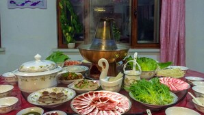 A dining table with various dishes, a hot pot, and several bowls and plates.