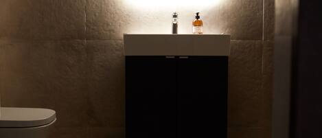 A bathroom with a toilet, a sink with a mirror above it, and a cabinet below.