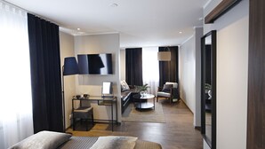 A modern hotel room with a bed, a desk, a sofa, and a TV. - Keflavik Micro Suites (Reykjanesbær)