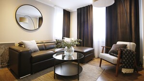 A modern living room with a leather sofa, a round coffee table, and a chair. - Keflavik Micro Suites (Reykjanesbær)