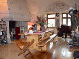 Un interior rústico con pared de piedra, muebles de madera, un piano y una estatua de un caballero.
