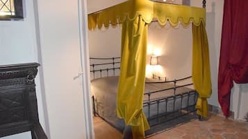 A room with a four-poster bed, a nightstand, and a lamp.