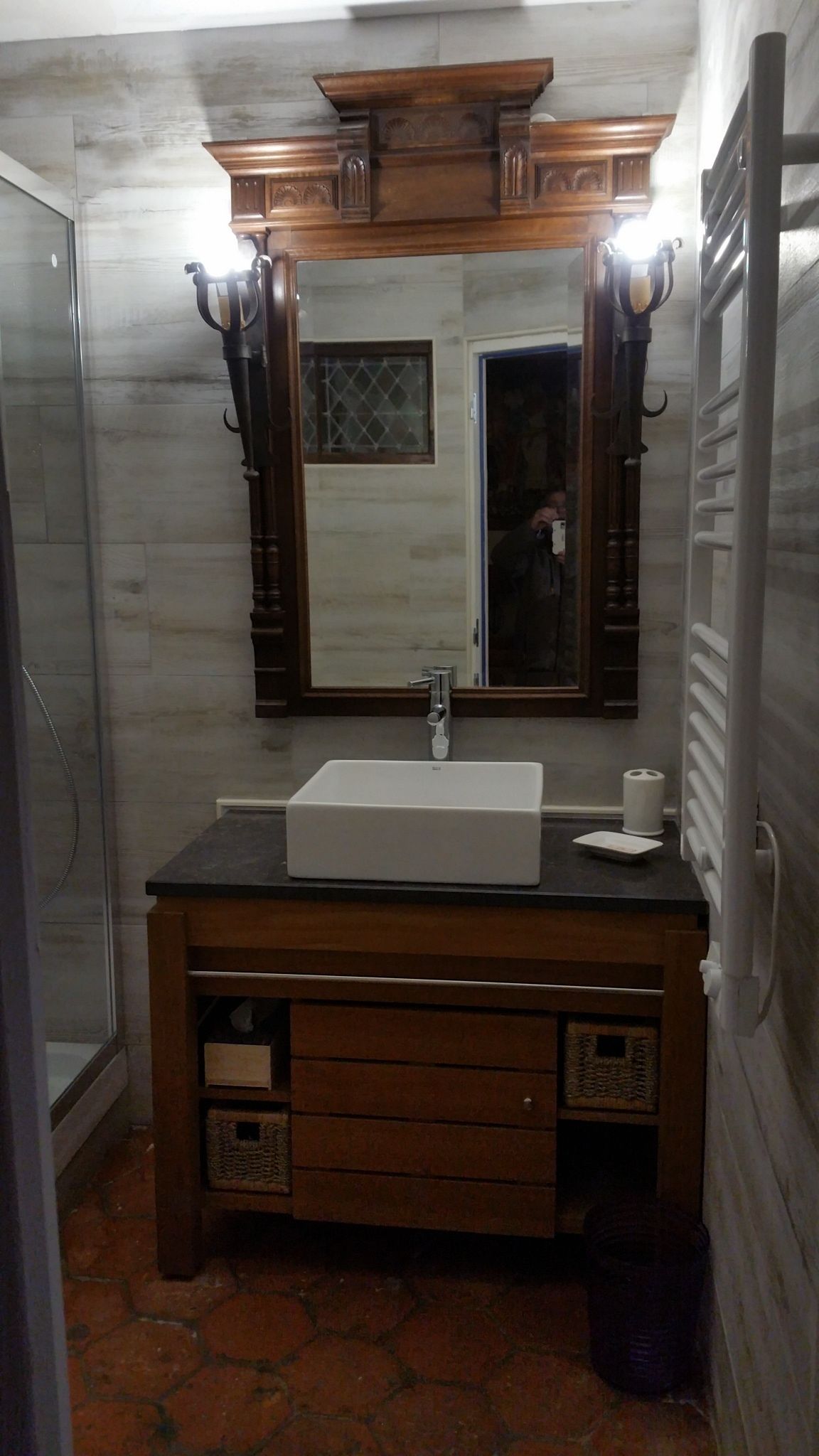 A bathroom with a wooden vanity, a large mirror, and a white sink.