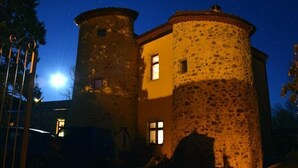 A stone building with a round tower and a rectangular section, illuminated by warm lighting.