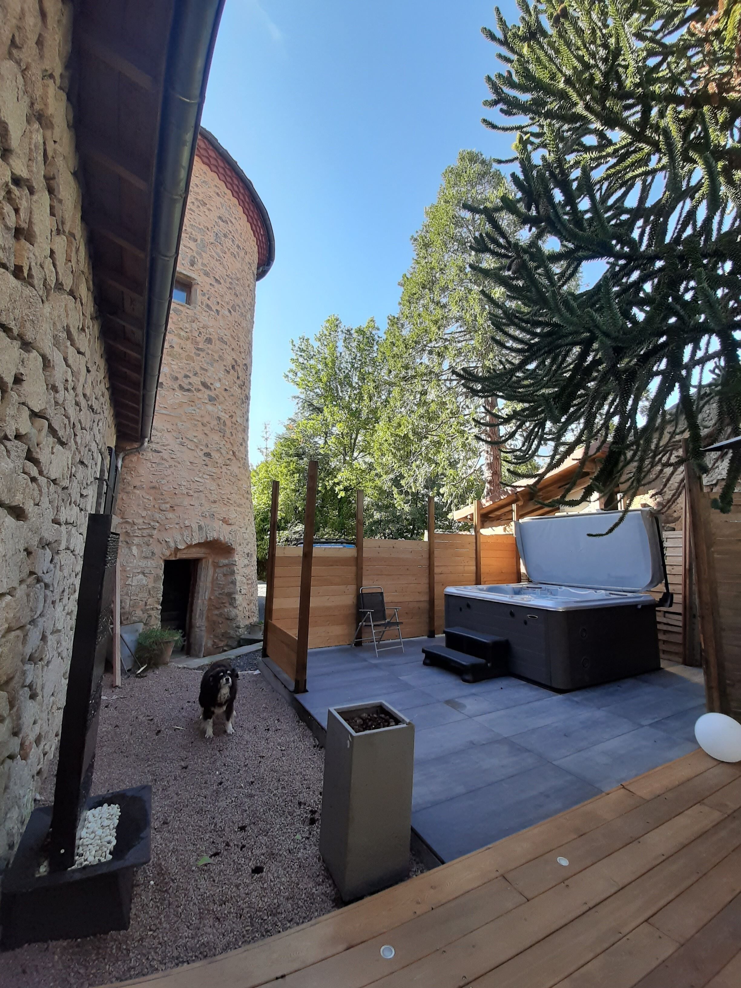 A stone building with a wooden deck, a hot tub, and a dog.