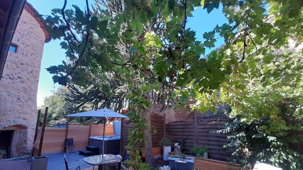 A wooden deck with outdoor furniture, a hot tub, and a pergola with a blue umbrella.