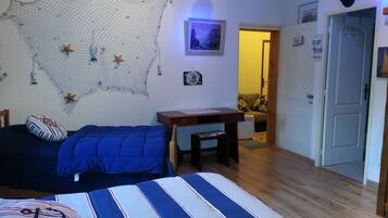 Een slaapkamer met een bed, een bureau en een stoel. Op de muur hangt een net met zeesterren, een foto en een deur.