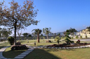 A landscaped park with a variety of trees, a stone pathway, and a well-maintained lawn.