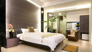 A modern bedroom with a large bed, bedside tables, a chair, and a plant. - Spring Fountain Hotel (Jiaoxi)