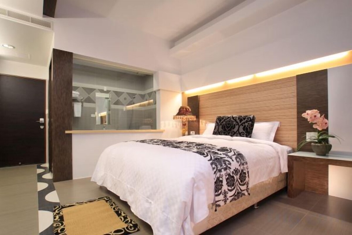 Habitació d'hotel moderna amb un llit gran, una taula de nit i un mirall.