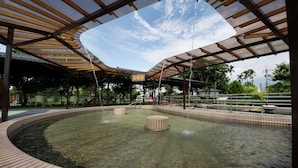 A covered outdoor area with a circular water feature, benches, and a shelter with a wooden roof. - Spring Fountain Hotel (Jiaoxi)