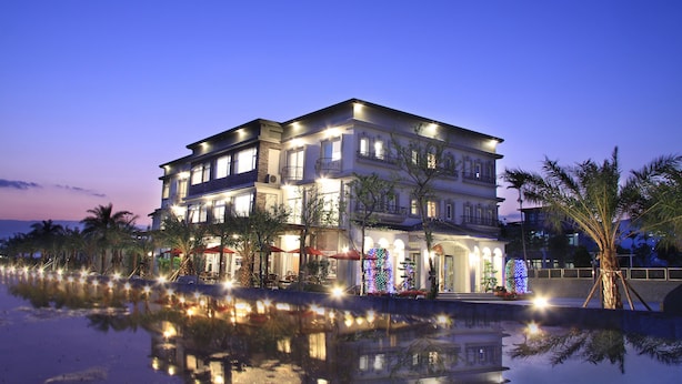 A multi-story hotel with a reflective pool in front, featuring a well-lit facade and outdoor seating area. - Spring Fountain Hotel (Jiaoxi)