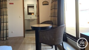 A hotel room with a round table, a wicker chair, a sink, and a mirror. - Discovery Apartment Carnaxide (Oeiras)
