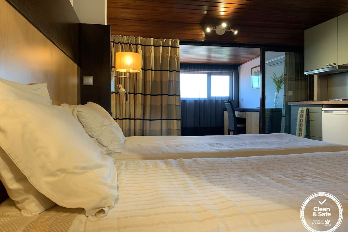 Ein Schlafzimmer mit einem großen Bett, einem Schreibtisch und einem Fenster mit Vorhängen.