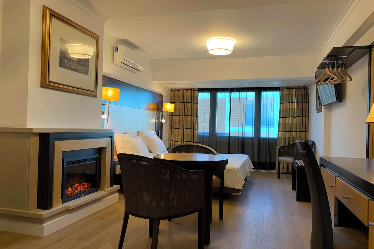 Ein Hotelzimmer mit Kamin, einem Bett, einem Esstisch und einem an der Wand befestigten Fernseher.